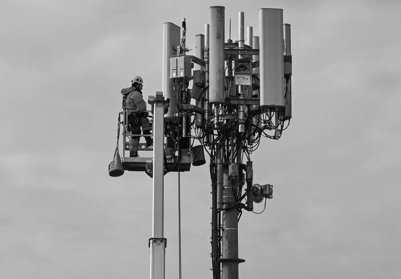 Techniker auf einer Hebebühne an einem Mobilfunkmast mit 5G-Antennen